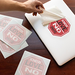 Stop sign decal being applied to a laptop with extra octagon shaped decals waiting nearby.