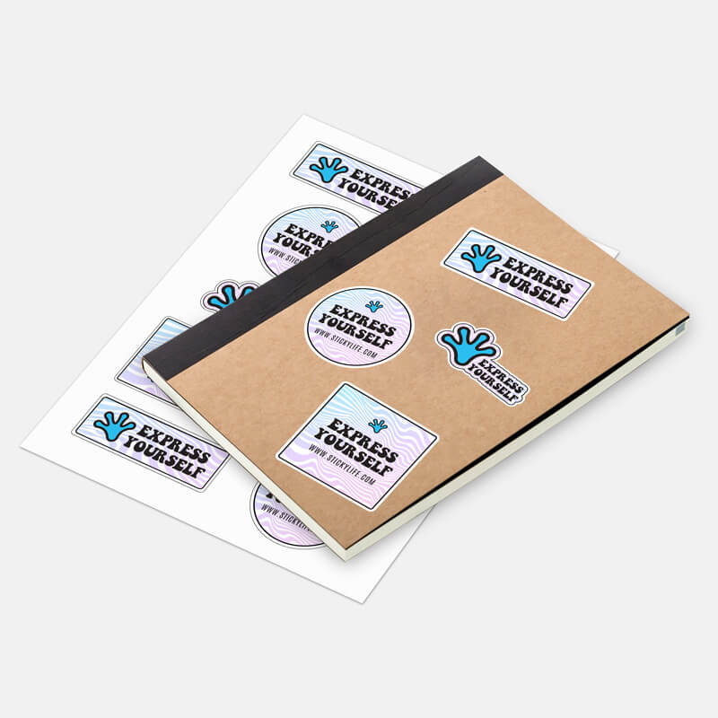A sticker sheet displayed alongside a notebook with applied stickers on a clean off white background.