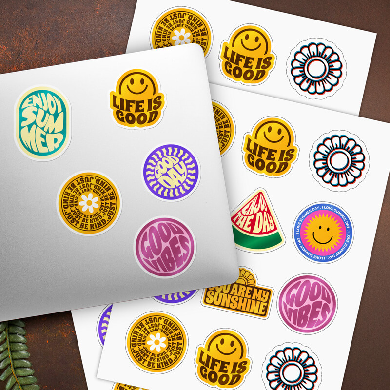 Sticker sheets with positive message designs, some applied to a laptop cover.