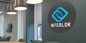 A black circle wall decal applied to a wall inside of an business office. The wall decal shows a company logo and reads the name of the business, which is Interlok.