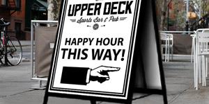An outdoor A-Frame sign placed on a sidewalk directing traffic towards a nearby local sports bar and pub.