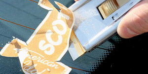 A decal being removed from a car window with a scraper.